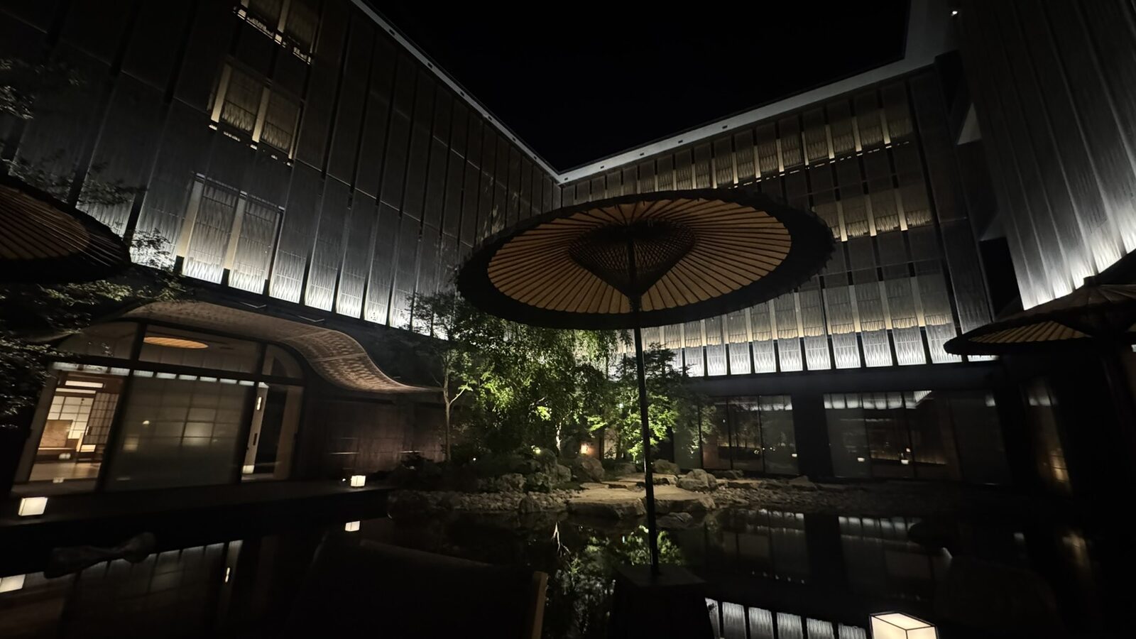 唐破風屋根と和傘、水盤が灯る中庭（夜）