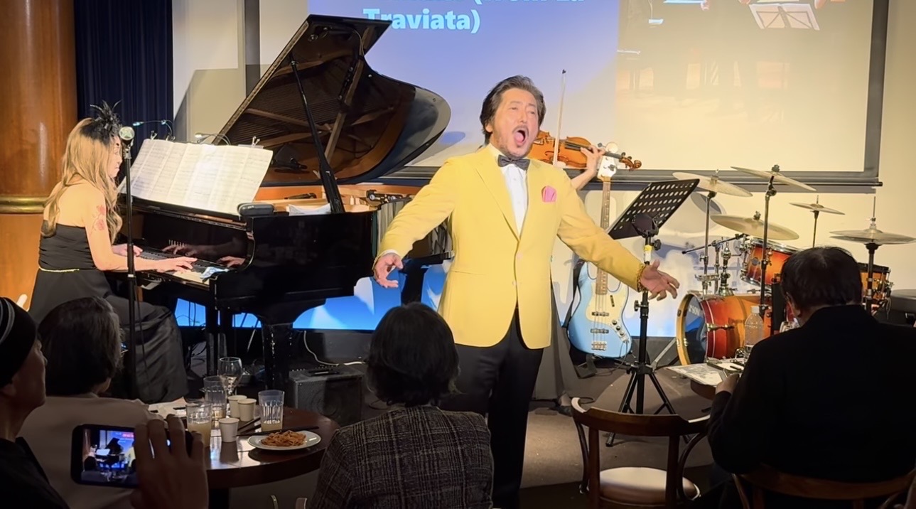 黄色ジャケットで歌唱する小栗成男